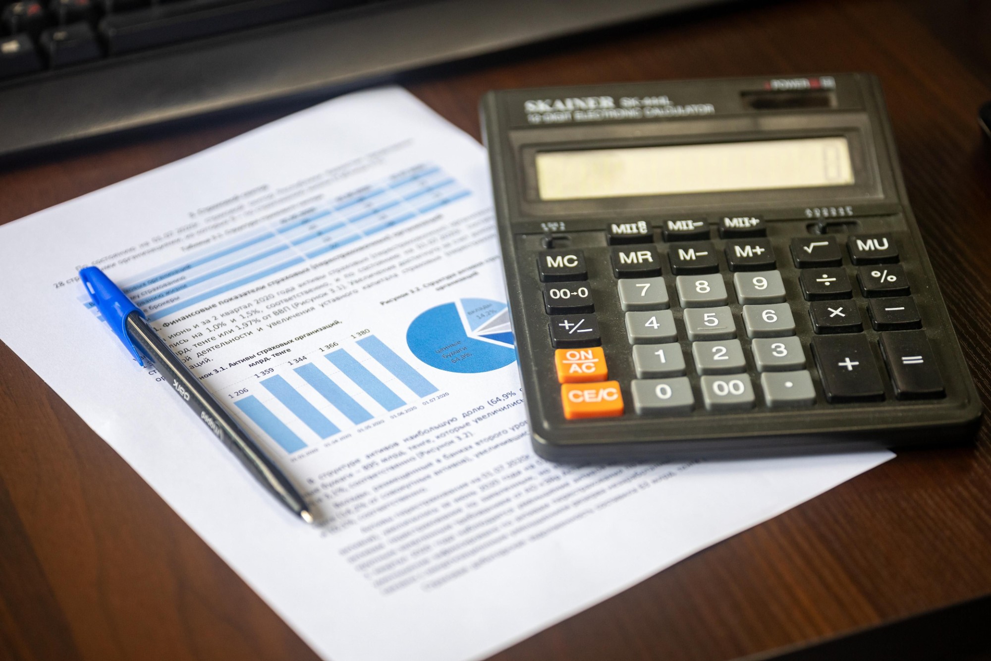 Calculator and pen on a printed financial report with charts